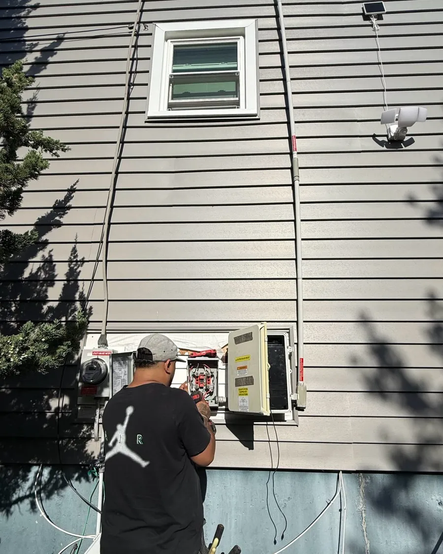 Gomes Electrical working on a meter and solar disconnect outside a home in Randolph